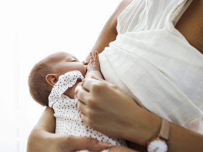 Mother breastfeeding and hugging newborn baby